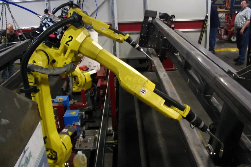 Zwei gelbe sechsachsige Schweißroboter in einer Fertigungszelle